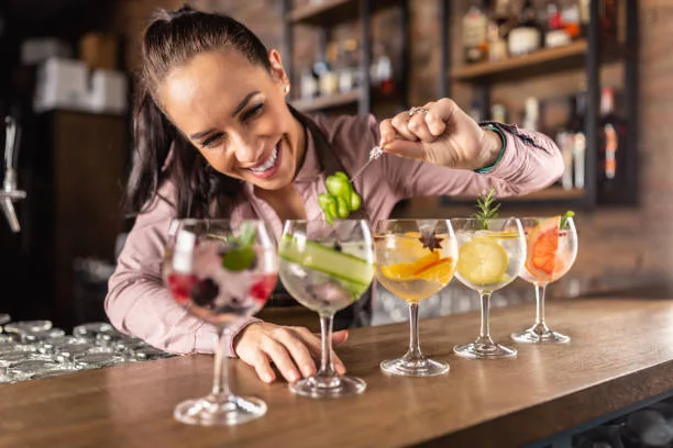 femme souriante préparant des cocktails colorés dans un bar à paris pendant un atelier evjf