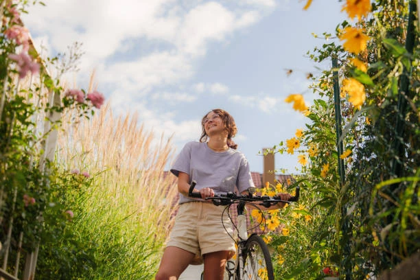 femme souriante tenant un vélo au milieu de fleurs lors d’une balade vélo evjf au touquet paris plage