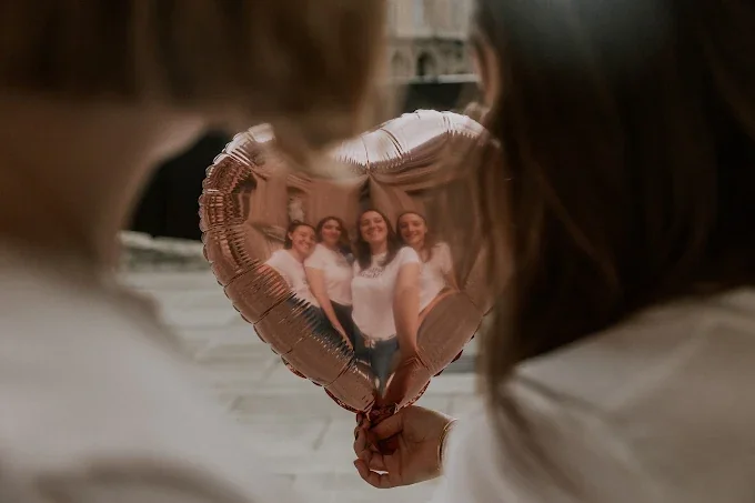 Reflet d’un groupe d’amies  dans un ballon en forme de cœur, i