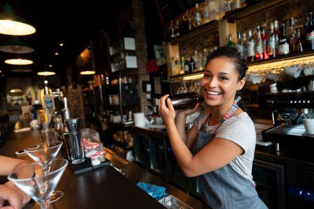 jeune femme avec bracelets au poignet barmaid souriante préparant un cocktail pendant un evjf au touquet paris plage dans une ambiance conviviale