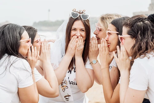 la mariee et ses amies rient ensemble sur la plage pendant une chasse au tresor evjf a biarritz