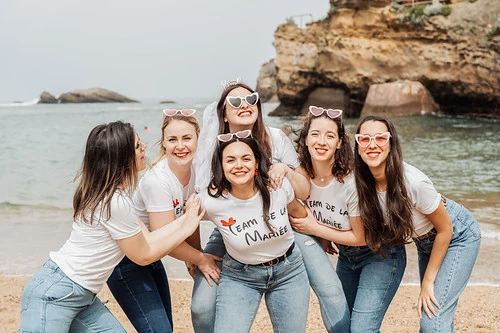 groupe de femmes souriantes en t shirt team de la mariee posant sur la plage pendant une chasse au tresor evjf a biarritz