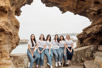 groupe de femmes en t shirt team de la mariee assises sous une arche rocheuse au bord de la mer 