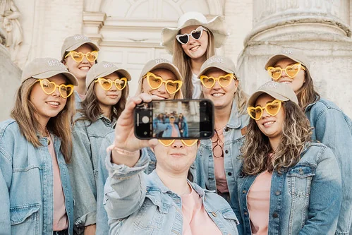 Groupe de femmes en lunettes cœur prenant un selfie pendant une chasse au trésor EVJF à Bruxelles.