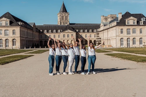 groupe de femmes en jeans et t shirts blancs levant les bras devant une abbaye