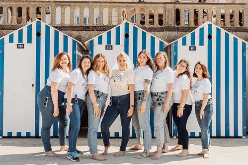 groupe de femmes en jeans et t shirts blancs posant devant des cabines de plage à cabourg pour une chasse au trésor evjf