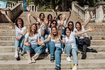 groupe de femmes souriantes levant les bras lors d’une chasse au trésor evjf à dijon sur des marches en plein air
