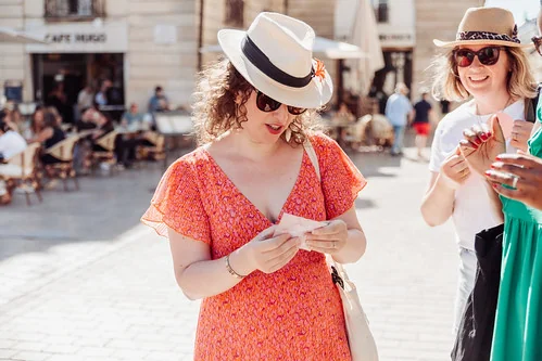femme en robe orange lisant un indice lors d’une chasse au trésor evjf à dijon sous un soleil d’été