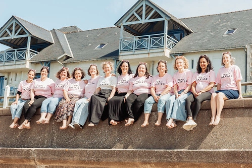 groupe de femmes assises sur un muret en t shirt rose lors d’une chasse au trésor evjf à la baule près d’une maison en bord de mer