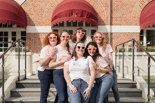 groupe de femmes souriantes en lunettes cœur posant devant un bâtiment lors d’une chasse au trésor evjf touquet paris plage