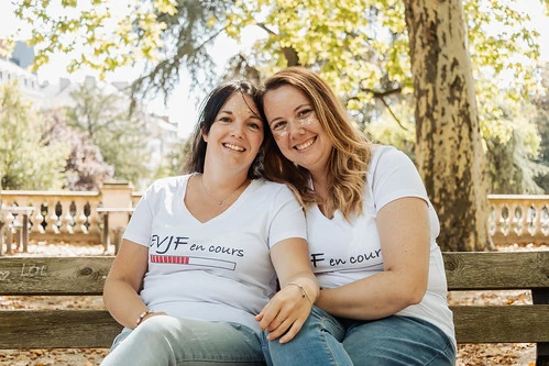 deux femmes souriantes assises sur un banc dans un parc 