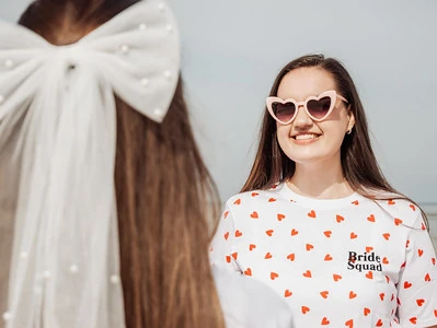 femme souriante avec des lunettes en forme de cœur et un t shirt bride squad
