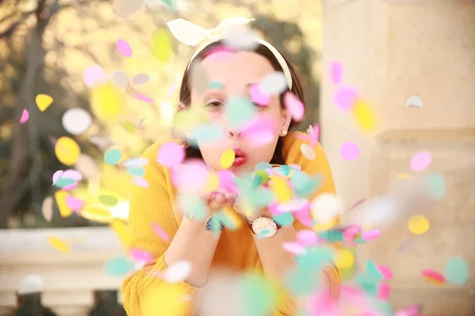 Femme soufflant des confettis colorés , symbole de fête et de joie,