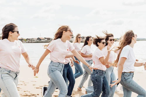 Groupe d’amies courant main dans la main sur la plage pendant un EVJF à Arcachon façon Koh Lanta.