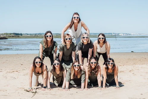 Groupe d’amies formant une pyramide humaine sur la plage pendant un EVJF à Arcachon inspiré de Koh Lanta.