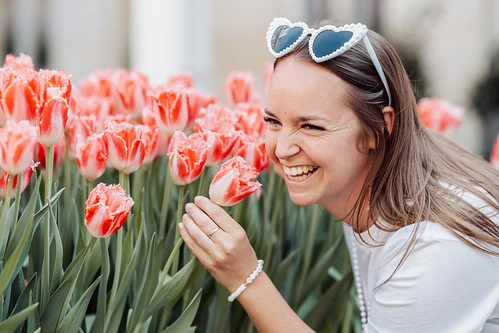femme souriante portant des lunettes en forme de cœur sentant des tulipes lors d’un evjf à amsterdam