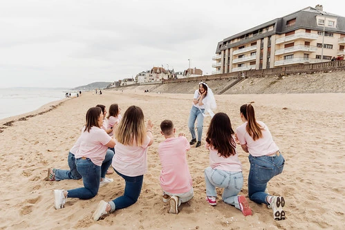 groupe d’amies en t shirts roses réalisant des defis et gages evjf sur la plage de cabourg autour de la mariée