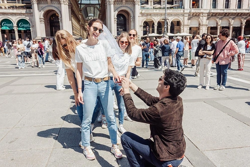 un homme fait une demande en mariage à une femme souriante entourée de ses amies lors d’un evjf à milan