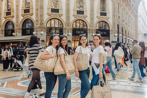 quatre femmes souriantes posant avec des sacs evjf dans la galerie vittorio emanuele ii à milan