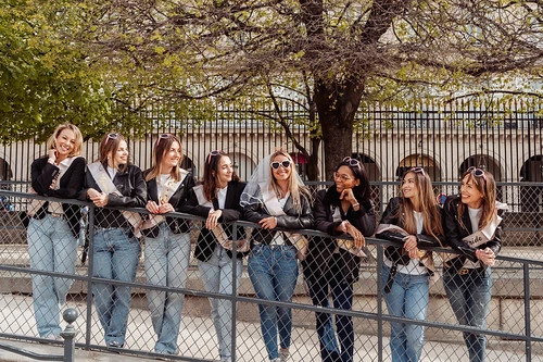 Groupe de jeunes femmes en veste noire et lunettes de soleil posant ensemble dehors pendant un escape game EVJF à Paris