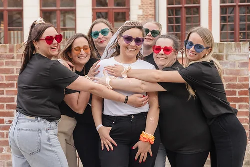 Groupe de femmes souriantes portant des lunettes colorées entourant la future mariée lors d’un EVJF à Lille