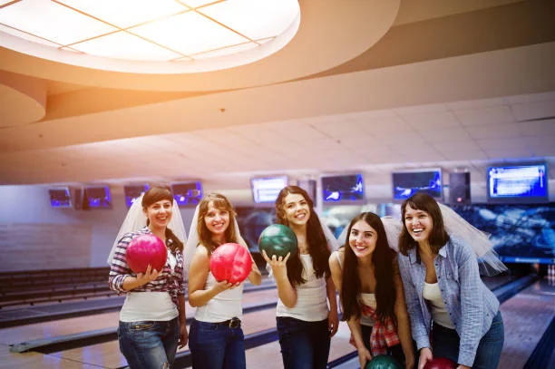 Groupe d’amies jouant au bowling à Dijon pendant un EVJF, souriantes et prêtes à passer une soirée festive, illustrant les 10 endroits où sortir à Dijon pendant un EVJF.