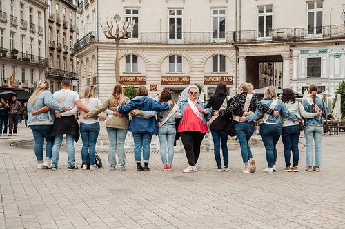 groupe de femmes en jean enlacées devant une fontainef