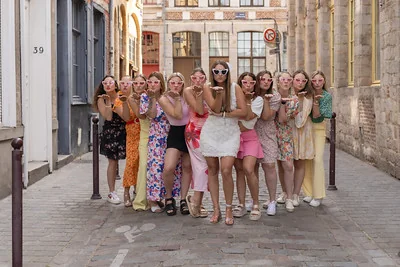 Groupe de femmes souriantes posant dans une rue pavée de Lille lors d’un EVJF, envoyant des baisers à l’objectif.