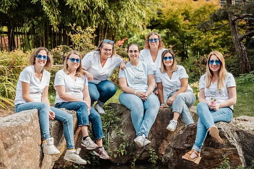 groupe d amies portant des lunettes bleues assises sur des rochers dans un jardin a nantes pendant un evjf