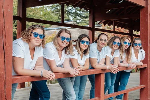 groupe d amies portant des lunettes bleues posant sur un pont en bois 