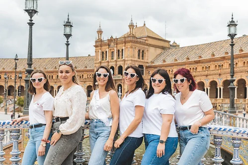 Groupe de femmes souriantes posant à la Plaza de España de Séville pendant un EVJF, ambiance festive et ensoleillée.