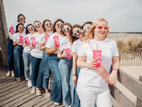 future-mariee-evjf-touquet-paris-plage future mariee et ses amies en t-shirt blanc et lunettes coeur posant sur une passerelle lors d’un evjf au touquet paris plage