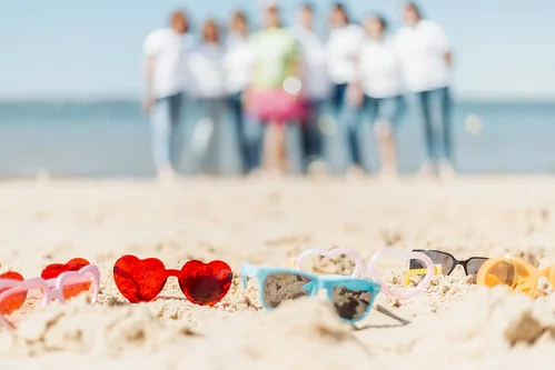 lunettes en forme de coeur posees sur le sable d arcachon avec un groupe de femmes evjf flou en arriere plan