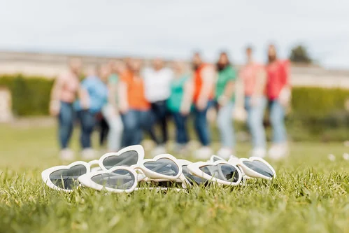 lunettes en forme de coeur posees sur l herbe avec un groupe de femmes flou en arriere plan pendant un evjf a bordeaux