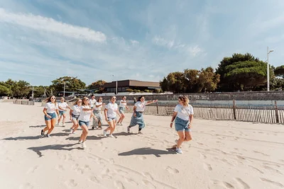 groupe de femmes courant et riant sur la plage des minimes à la rochelle pendant un evjf