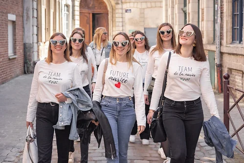 groupe de femmes en t-shirts evjf marchant dans les rues de lille avec la future mariee au centre
