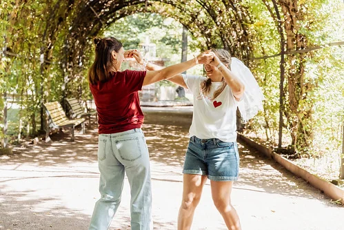 deux femmes dansent ensemble dans un parc de strasbourg pendant un evjf ensoleille