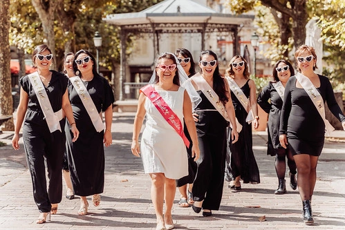 groupe de femmes en tenue noire marchant avec la future mariée lors de gages et défis evjf aix les bains dans un parc ensoleillé