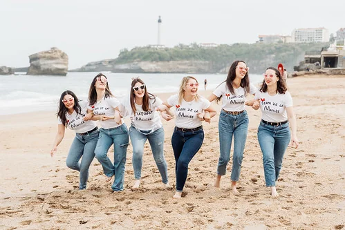 groupe d amies en t shirt team de la mariee courant sur la plage de biarritz pendant les gages et defis evjf