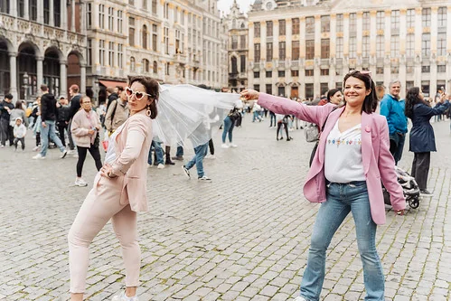 deux femmes en tenue rose s amusant sur la grand place de bruxelles pendant un evjf et realisant des gages et defis