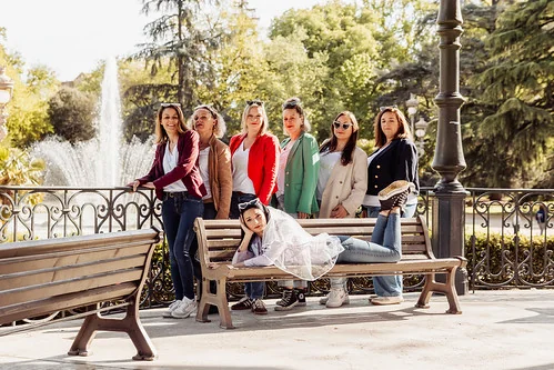 groupe de femmes posant dans un jardin de toulouse pendant un evjf avec la future mariee allongee sur un banc lors des gages et defis