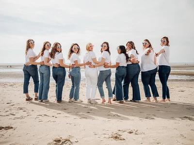 groupe-evjf-touquet-paris-plage groupe de femmes en jean et t-shirt blanc posant sur la plage lors d’un evjf au touquet paris plage