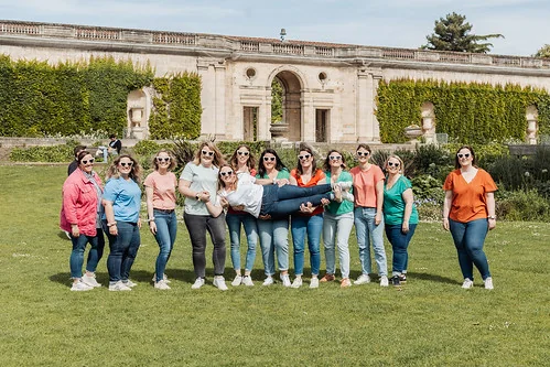 groupe de femmes en t shirts colores portant la future mariee pendant un koh lanta evjf a bordeaux dans un parc