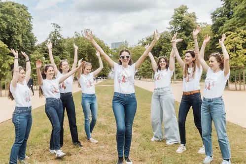 Groupe de femmes participant à une activité Koh Lanta EVJF à Bruxelles, levant les bras en signe de victoire dans un parc.