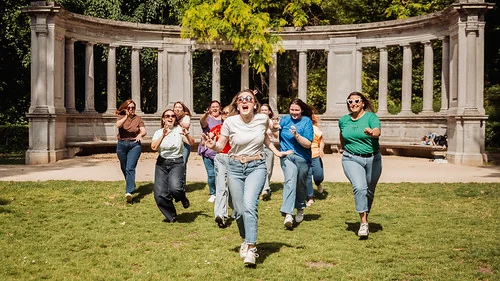 Groupe de femmes courant et riant ensemble lors d’une activité Koh Lanta EVJF à Bruxelles dans un parc verdoyant.