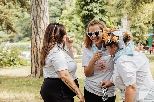trois femmes rient ensemble lors d un koh lanta evjf a dijon dans un parc en tenue assortie avec bandanas bleus
