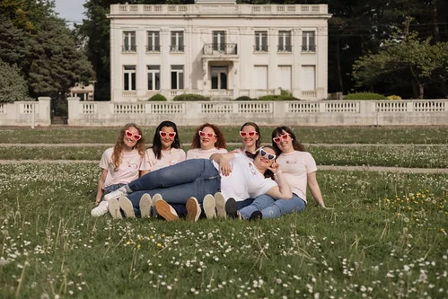 groupe de femmes portant des lunettes rouges posant allongées dans un parc du touquet pendant un koh lanta evjf paris plage