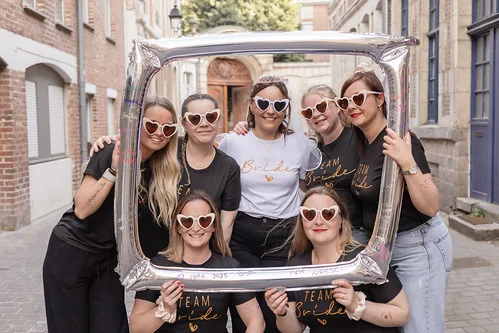 Groupe de femmes Team Bride souriantes posant avec un cadre lors d’un EVJF à Lille dans une rue du Vieux-Lille.