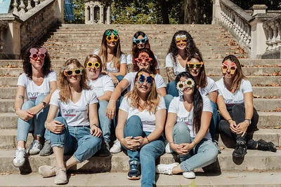 groupe de femmes en t shirts blancs et lunettes fantaisie pose sur des escaliers a dijon 