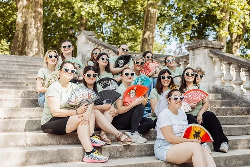 groupe de femmes portant des lunettes coeur et tenant des eventails poses sur des escaliers a dijon pendant un evjf avant de profiter des meilleurs brunchs pour un evjf a dijon